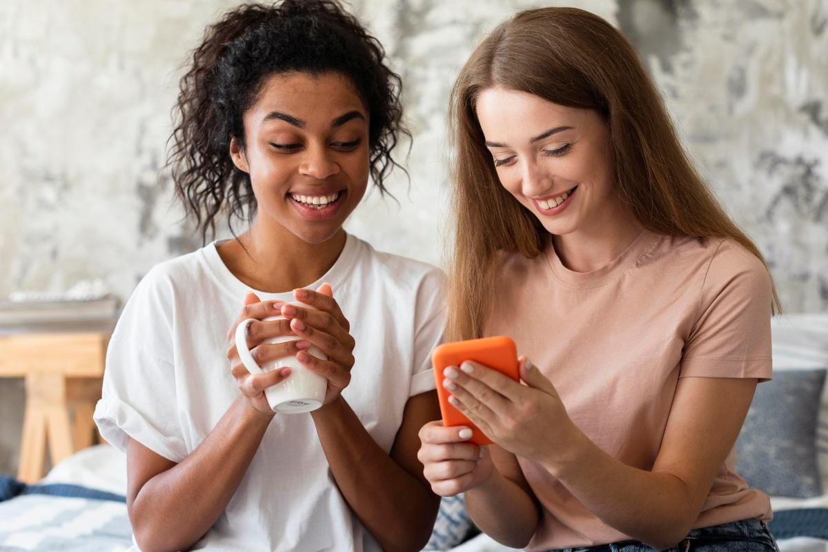 Como captar clientes pelo WhatsApp: 10 estratégias para atrair e converter 1 Duas mulheres olhando um celular e conversando com uma empresa pelo WhatsApp