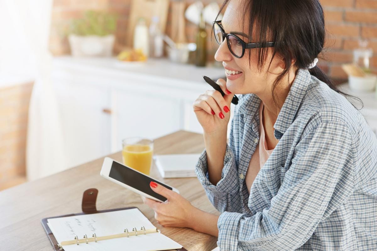 Como captar clientes pelo WhatsApp: 10 estratégias para atrair e converter 3 Mulher planejando a prospecção de clientes com celular e agenda na mão